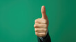© Zainab - Man doing happy thumbs up gesture with hand on green background