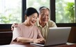 © COC STUDIO - Middle-aged couple sitting together, using a laptop for various activities.