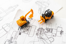 Desktop With Blueprint Yellow Mini Excavator, Ruler And Pencil Symbolizing The Wish To Build Own Home