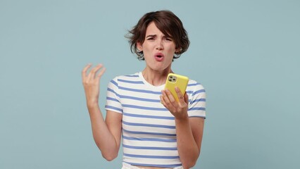 Wall Mural - Sad upset young woman wearing striped t-shirt casual clothes hold use mobile cell phone swear read bad fake news unexpected rumor has some problem isolated on pastel plain light blue cyan background