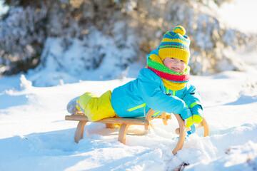 Wall Mural - Baby boy on sled. Child sledding. Kid with sledge