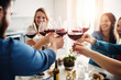 © Jasmina - Group of friends toasting with red wine glasses at a festive lunch party