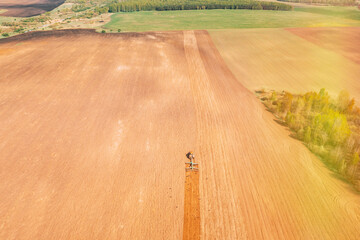 Wall Mural - Top View Tractor Plowing Field In Spring Season. Beginning Of Agricultural Spring Season. Cultivator Pulled By A Tractor In Countryside Rural Field Landscape. Birds In Flock Following For tractor.