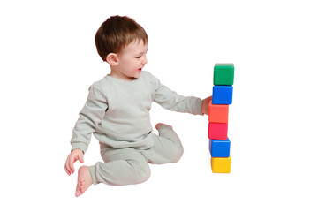 Wall Mural - Happy toddler baby plays with cubes on studio, isolated on white background. Child boy builds a tower of toys, isolated on white background. Kid age one year eight months, full height