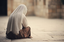 A Rear View Of A Muslim Woman Sitting On The Ground In The Street. Prayer For Peace