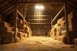 A barn filled with lots of hay next to a light. This image can be used to depict a traditional farm setting or to symbolize abundance and preparation.