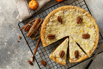 Wall Mural - Fall traditional pie pumpkin with crumble and pecan on a gray stone background. Thanksgiving dessert. View from above. Copy space.