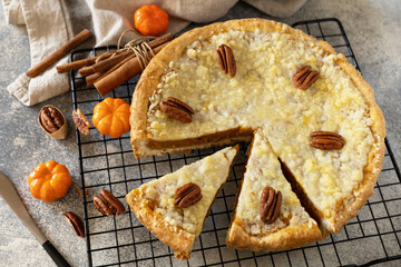 Canvas Print - Fall traditional pie pumpkin with crumble and pecan on a gray stone background. Thanksgiving dessert.