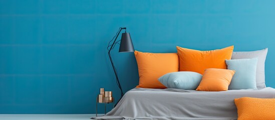 Wall Mural - Orange blue and gray pillows arranged on a blue bed With copyspace for text