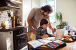© Marko Geber - Young father helping his son with online class on a laptop at home