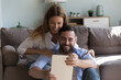 © fizkes - Happy millennial handsome husband and cheerful wife using tablet together, getting good news, smiling, laughing, sitting close in home living room, sharing digital gadget for online communication