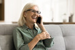Cheerful pretty retired elderly woman in glasses speaking on cell, laughing, showing healthy white teeth, having fun, enjoying communication, wireless connection, conversation, phone call