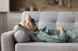 © fizkes - Calm senior sleepy woman napping at home, lying on back on sofa with closed eyes, sleeping on comfortable couch, relaxing in living room, covering eyes with arm, enjoying relaxation, leisure