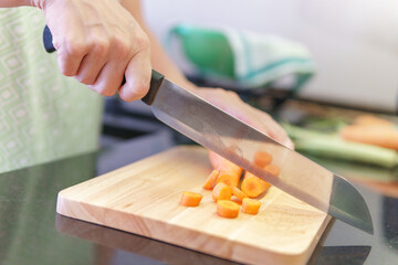 Canvas Print - Woman hands cutting fresh orange carrots in a kitchen