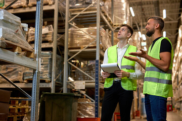 Men warehouse workers talking,warehouse industry and logistics concept . two young workers in uniform discuss together. Concept of good management system to support working with industrial business.