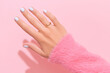 Womans hand with white nail design on pink background. Manicure, pedicure beauty salon concept