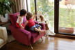 © Lisa Tichané - Young boy and baby girl sitting on an armchair at home giving their dog a biscuit