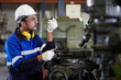 © offsuperphoto - factory worker or technician looking and checking screw beside lathe machine in the factory