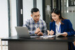 © laddawan - Female discussing new project with male colleague. Young woman talking with young man in office..