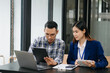 © laddawan - Female discussing new project with male colleague. Young woman talking with young man in office..