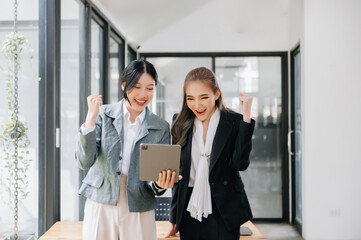 Two Asian businesswoman and man discuss investment project working and planning strategy with tablet laptop computer in office..