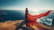 © Anna - Woman in red dress standing on a cliff by the sea. The wind blows in the long veil. Creativity portrait photography. Travel and fashion concept. AI generative.