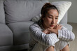 © amenic181 - Lonely Asian woman in distress, worried, confused, sitting on floor at home. Female suffer from mental health problems.