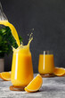 orange juice pouring into glass with splash on table