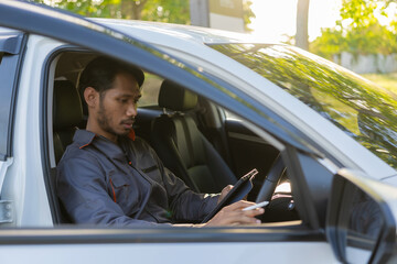 Auto mechanic inspects car by inspecting and writing checklist on clipboard. Mechanic checks car parts stock on laptop computer with car broken down on the side of the road