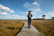 © Rob Wilkinson - Mid adult woman walking on a wooden boardwalk through marshland, keeping fit and healthy.