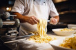 Chef making fresh tagliatelle with a traditional pasta machine