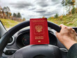 Russian passport in hand of driver woman. Russian cars banned for entering in Europe. Russian tourism closed during war of Russia and Uk. Confiscation of Russian car and sanctions against Russian