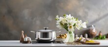 Cooking using stainless steel saucepan on induction hob with lid eggs towel flowers in glass vase on kitchen worktop with light walls