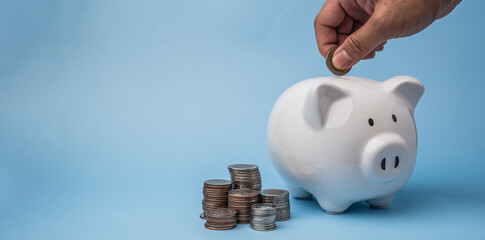 Man hand putting a coin into piggy bank on background. Business wealth saving money financial planning and investment concept.