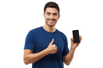 Young man holding blank phone, smiling at camera, showing thubms up gesture