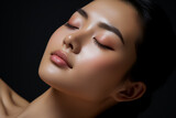 Fototapeta  - Asian woman applies skin tonic to cheek with closed eyes 