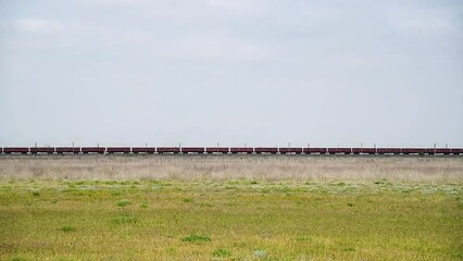 Wall Mural - Locomotive pulls a very large and heavy freight train with wagons and tank cars along a railway