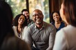 © Stavros - Group therapy and support. The focus is on a smiling middle aged African American man in eyeglasses. A group of people around support him.
