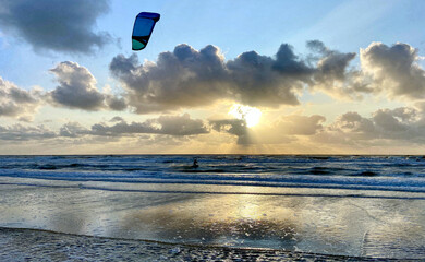 Wall Mural - Kitesurfers on the rough Dutch North Sea at sunset. Egmond aan Zee, the Netherlands, Europe. 