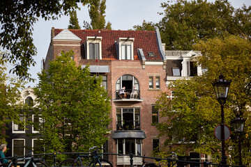 Canvas Print - A nice building with a cute balconies and green trees in front of the house, selective focus