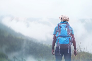 Wall Mural - African traveler man in hat standing and looking to the beautiful nature of the mountains on a foggy day.Adventure travel and success concept