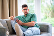 © gzorgz - Confident mid aged man sitting on the couch at home and using digital tablet