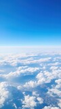 Fototapeta Niebo - Panoramic view of fields and clouds from an airplane window. The sky is a bright blue with fluffy white clouds.
