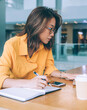 © BullRun - Thoughtful woman working on laptop and taking notes