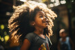 Portrait of a happy young black girl smiling thrilled, with big curly hair in sunny blurred background outdoors wearing a t shirt and earrings, intense expression playful smile afro american child