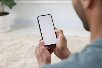 Wall Mural - Man using modern mobile phone indoors, closeup