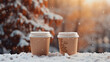 ボケた雪景色を背景に、テイクアウトのホットコーヒー2つが雪の上に置かれている