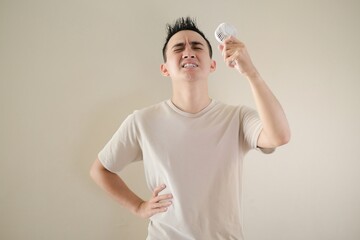 young asian man is feeling bad mood because of the hot weather condition