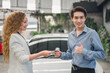 A beautiful female car sales employee gives the keys to the customer who has duly signed the purchase contract. Car rental, dealership successful sale of a car, purchase contract, and delivery of key.
