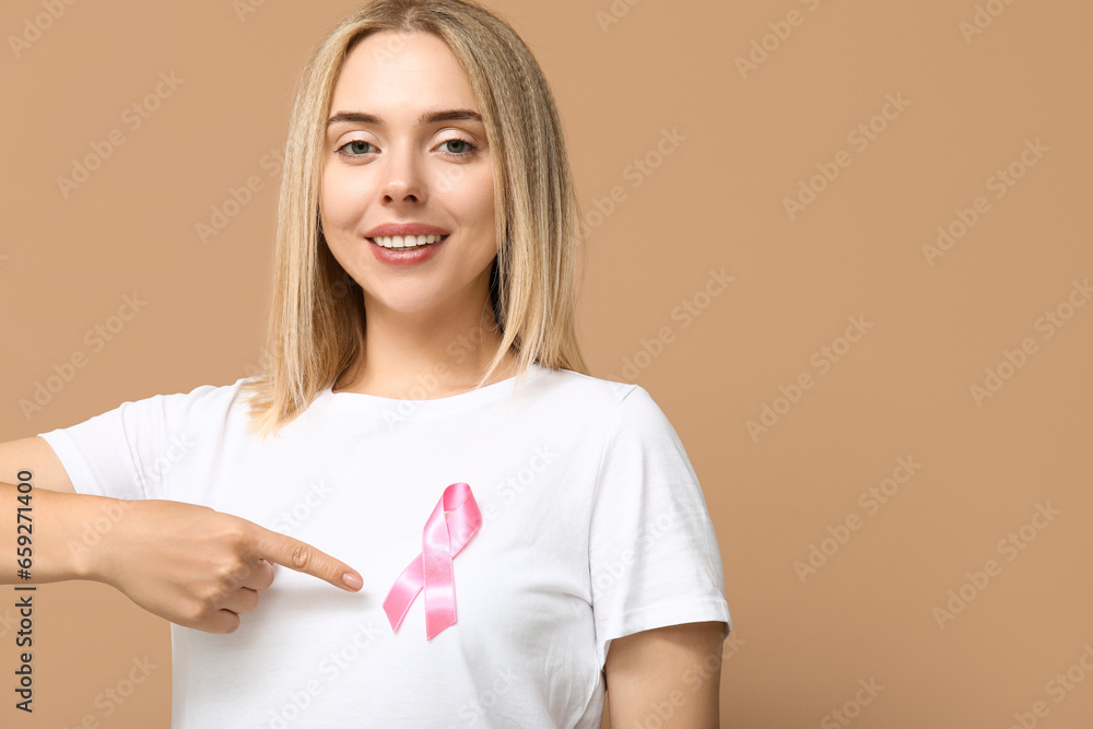 Young woman with pink ribbon on beige background. Breast cancer awareness concept